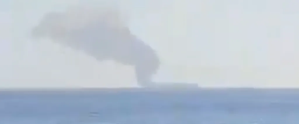A commercial tanker emitting thick smoke off the Oman coast near the Strait of Hormuz.