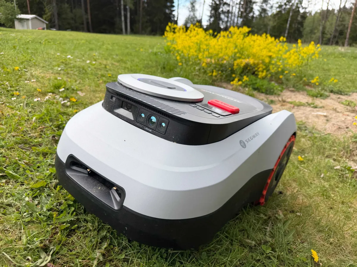 Segway Navimow i210 LiDAR autonomous mower cutting grass in a residential yard with visible top sensors.