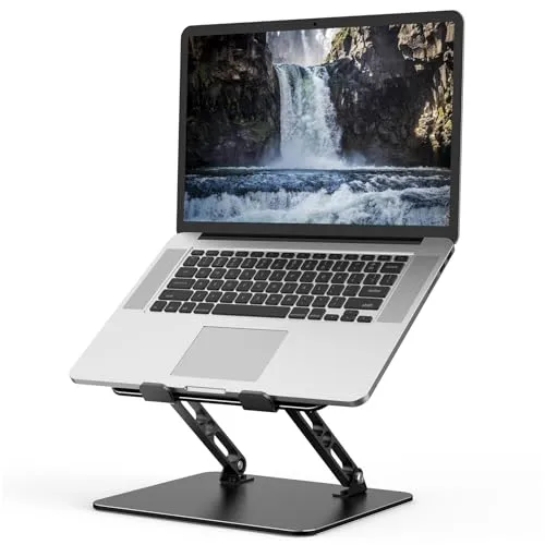 MacBook on a raised stand with external keyboard, mouse, and adjustable desk lamp