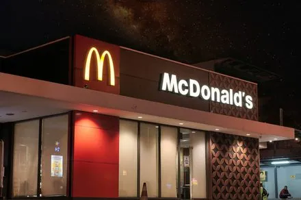 A McDonald's drive-thru lane with a voice ordering speaker and a waiting vehicle.