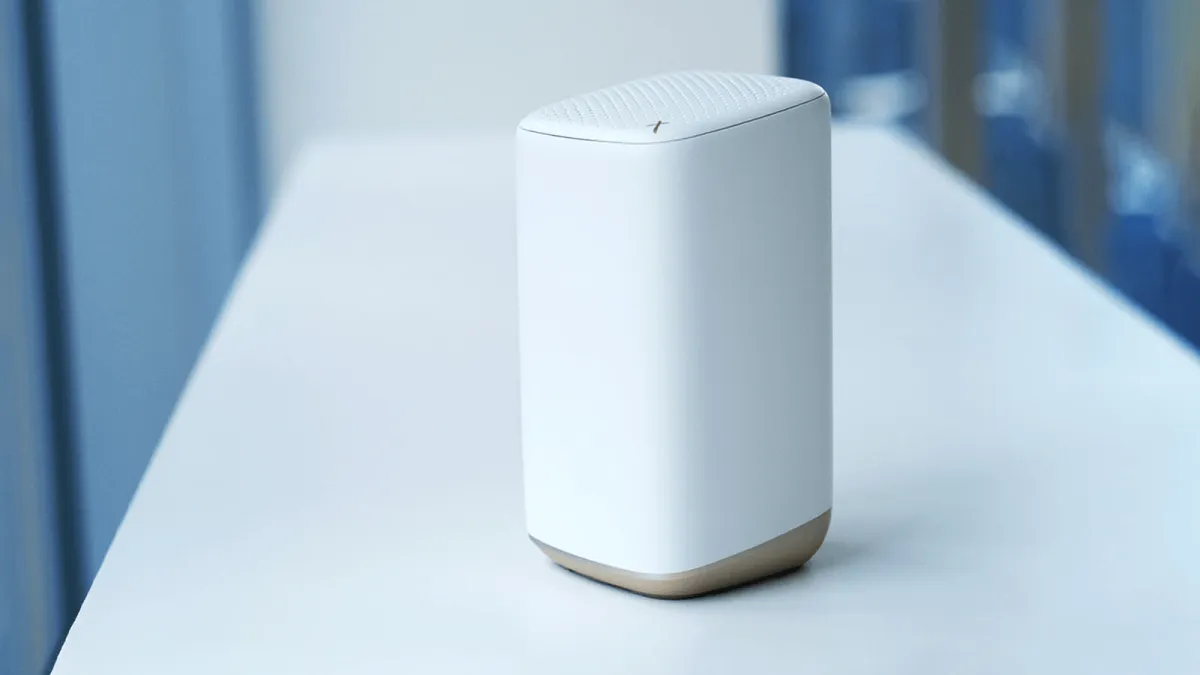A white Xfinity wireless router sits on a wooden desk.