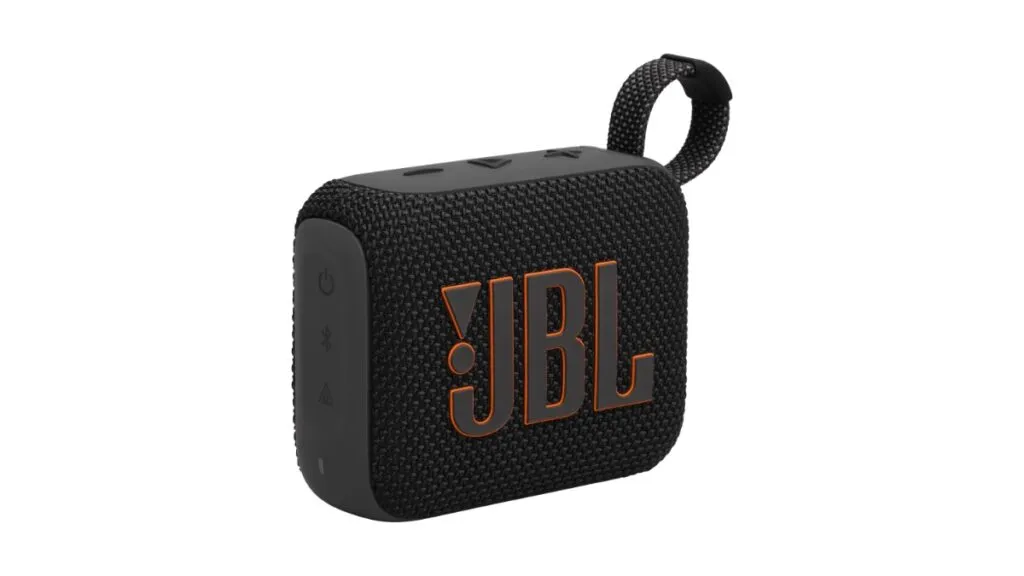 A compact JBL Go 4 waterproof speaker rests on outdoor terrain.