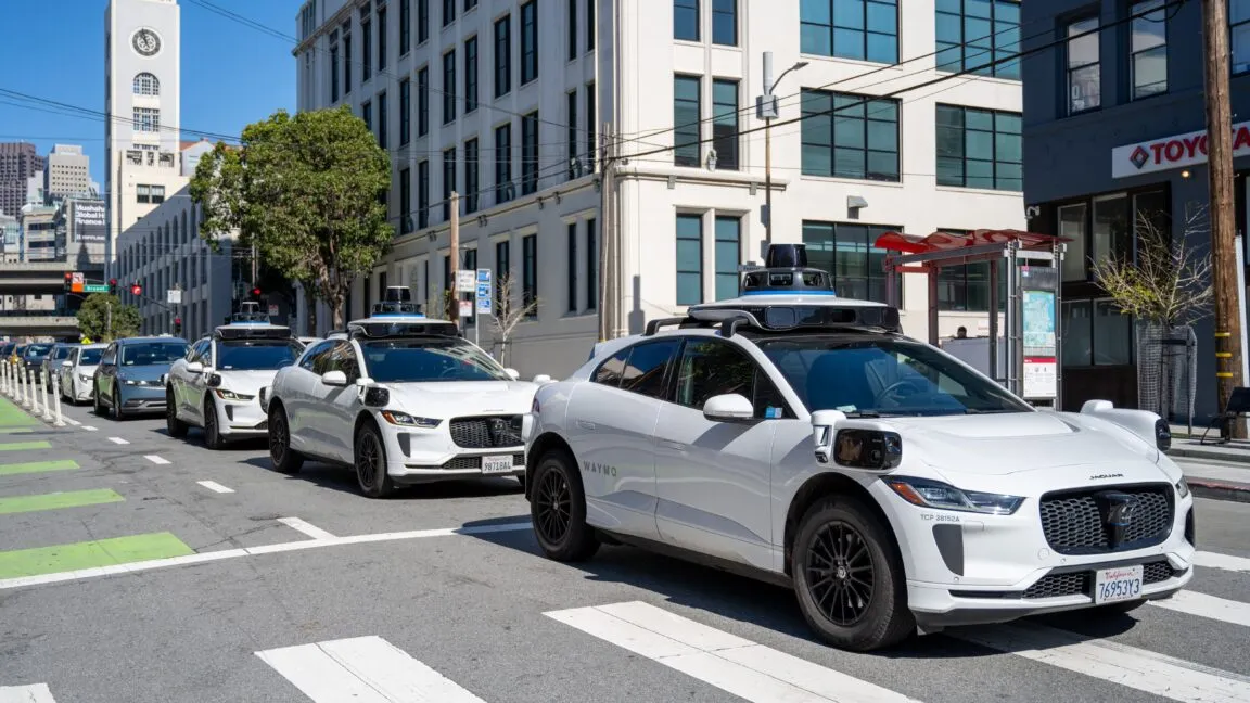 Autonomous vehicles travel through congested city streets without passengers.