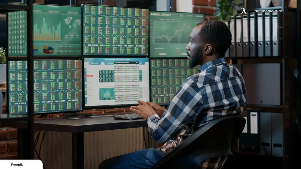 A professional trading desk features six monitors displaying financial charts and real-time market data.