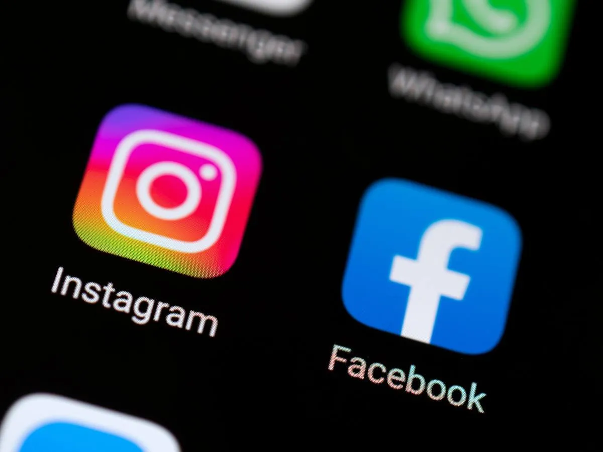 A computer monitor displays a security alert regarding compromised Instagram accounts and Meta AI vulnerabilities.
