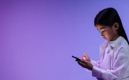 A child holding a smartphone while a parent encourages basic mobile devices for healthier development.