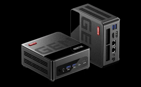 A compact desktop computer on a desk, showing its small chassis and rear connectivity ports.