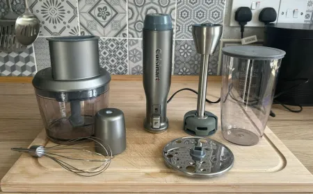 A silver Cuisinart immersion blender with blending and whisk attachments rests on a kitchen counter.
