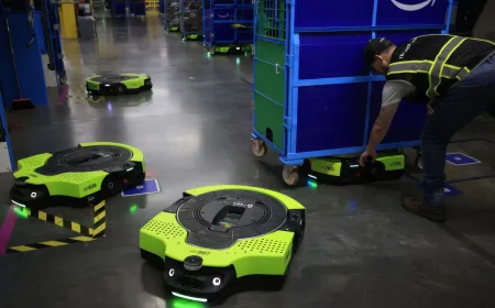 An autonomous Proteus warehouse robot navigates a facility while transporting a heavy inventory cart.