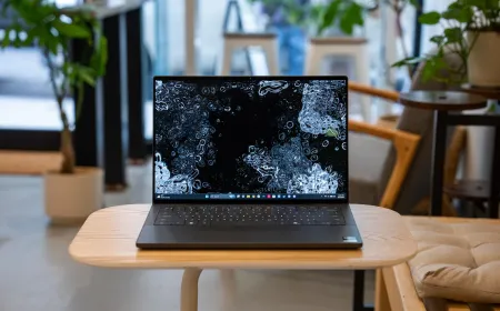 A silver Dell XPS 14 laptop rests open on a desk with its screen illuminated.