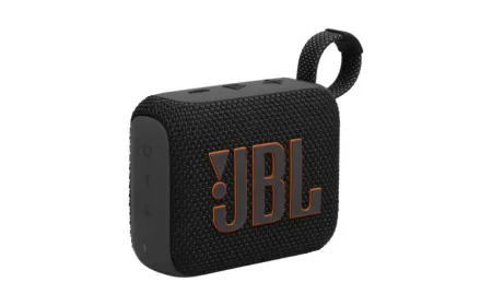 A compact JBL Go 4 waterproof speaker rests on outdoor terrain.