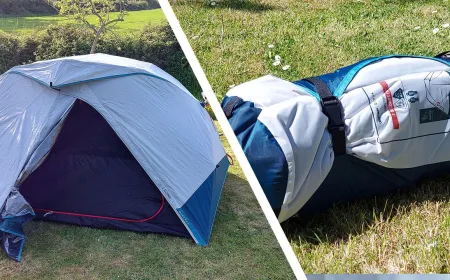 A compact camping tent stands fully assembled on a grassy field with its rainfly secured and frame aligned.