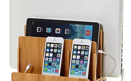 A neatly arranged desk displays an iPhone on a charging stand alongside cables and accessories for ergonomic access.