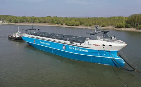 An autonomous cargo ship navigates open waters while maritime regulators draft safety guidelines.