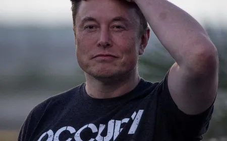 Elon Musk stands beside a financial chart marking his net worth crossing one trillion dollars.