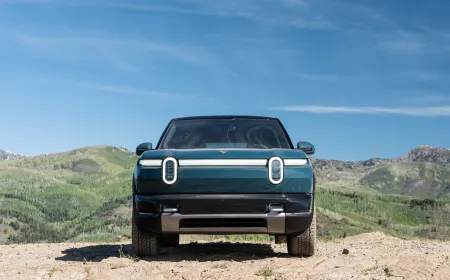 The 2027 Rivian R2 electric SUV is parked on a paved road during a first drive review.