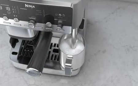 The compact Ninja Luxe Cafe Mini Plus espresso machine displays its control panel and integrated milk frothing spout.