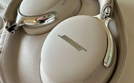 Bose QuietComfort Ultra Headphones and Ultra Open Earbuds sit on a retail display surface.