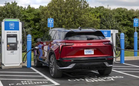A General Motors electric vehicle connects to a public charging station while demonstrating vehicle-to-grid power transfer.