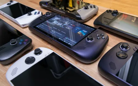 A handheld gaming PC rests on a desk. The screen displays a game interface.