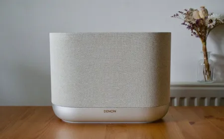 The Denon Home 400 wireless speaker features a cylindrical fabric enclosure with integrated touch controls.