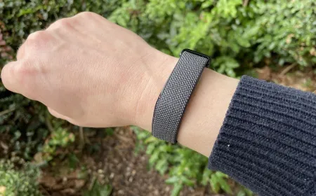 The Google Fitbit Air screenless fitness band rests on a display stand. Its minimalist design emphasizes comfort.