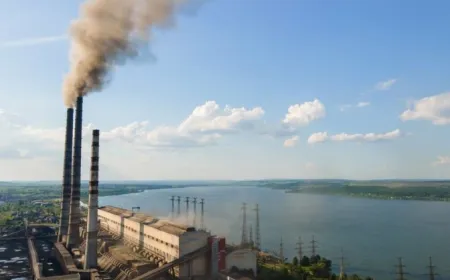 Smokestacks at a coal power plant release steam during daytime operations.